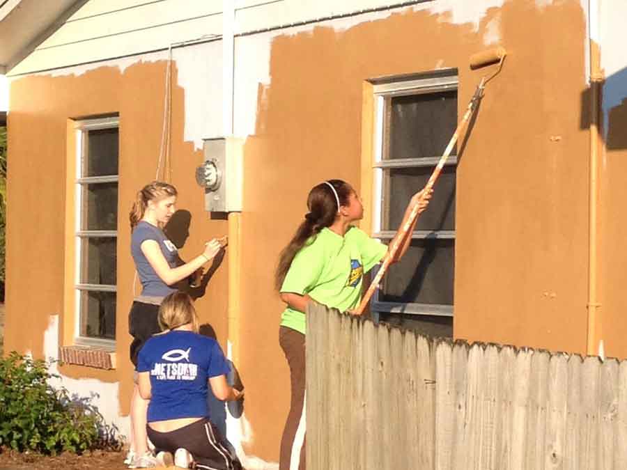 Girls painting exterior building wall
