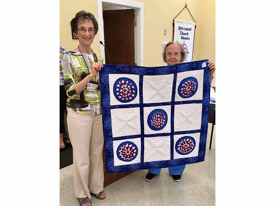 President Helen Marner and friend holding up quilt 