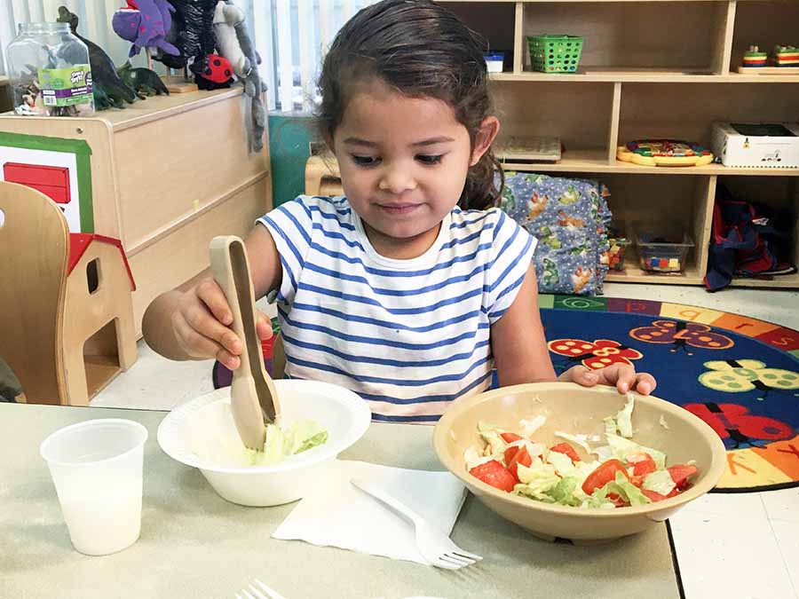 Young girl getting bowl of salad