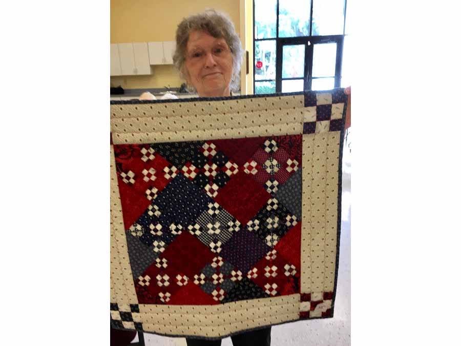 Marcia Haberman holding up quilt she made
