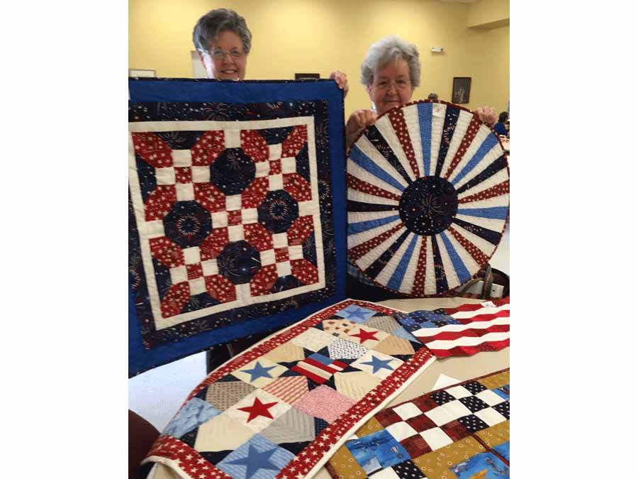 Roberta McCullough and Judy White displaying some of the quilts made at the guild