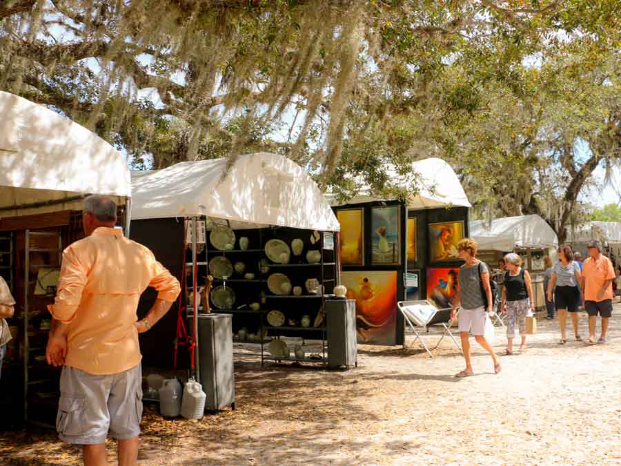 People looking at artwork in tents at the Under the Oaks Art Festival Vero Beach Florida
