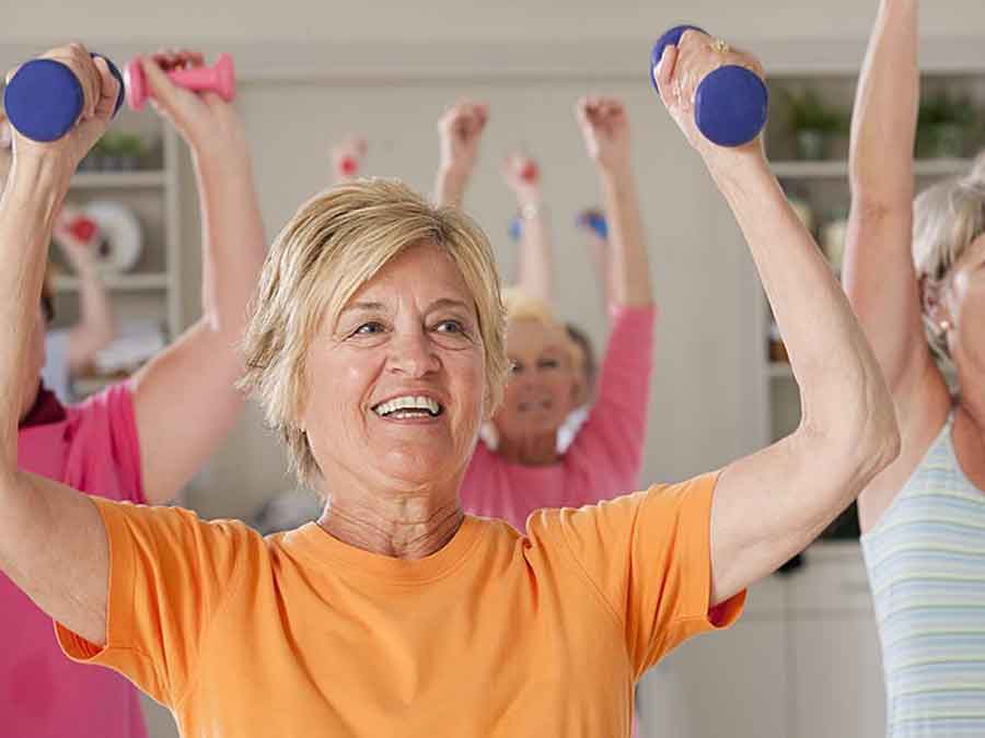 women holding dumb bells while doing exercises in class